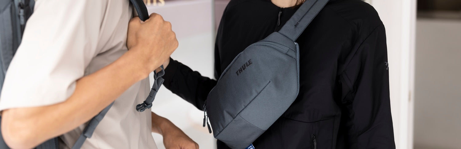 Two travelers wearing lightweight backpacks and crossbody sling bags while meeting in an urban setting.