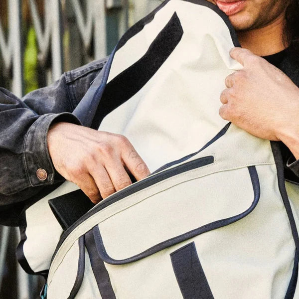 Close-up of hands opening the flap of a sage green Chrome Citizen 15L messenger bag