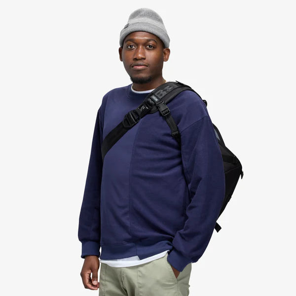 Man wearing a black Chrome Citizen 15L messenger bag crossbody over a navy sweater