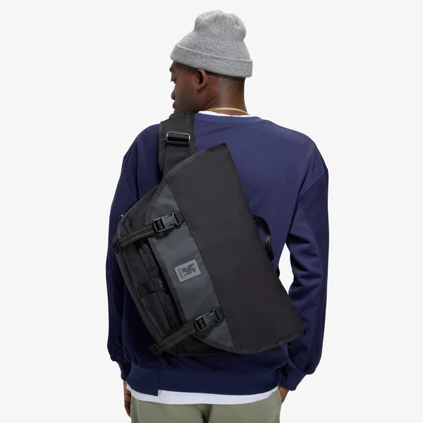 Man wearing a black Chrome Citizen 15L messenger bag across his back, rear view
