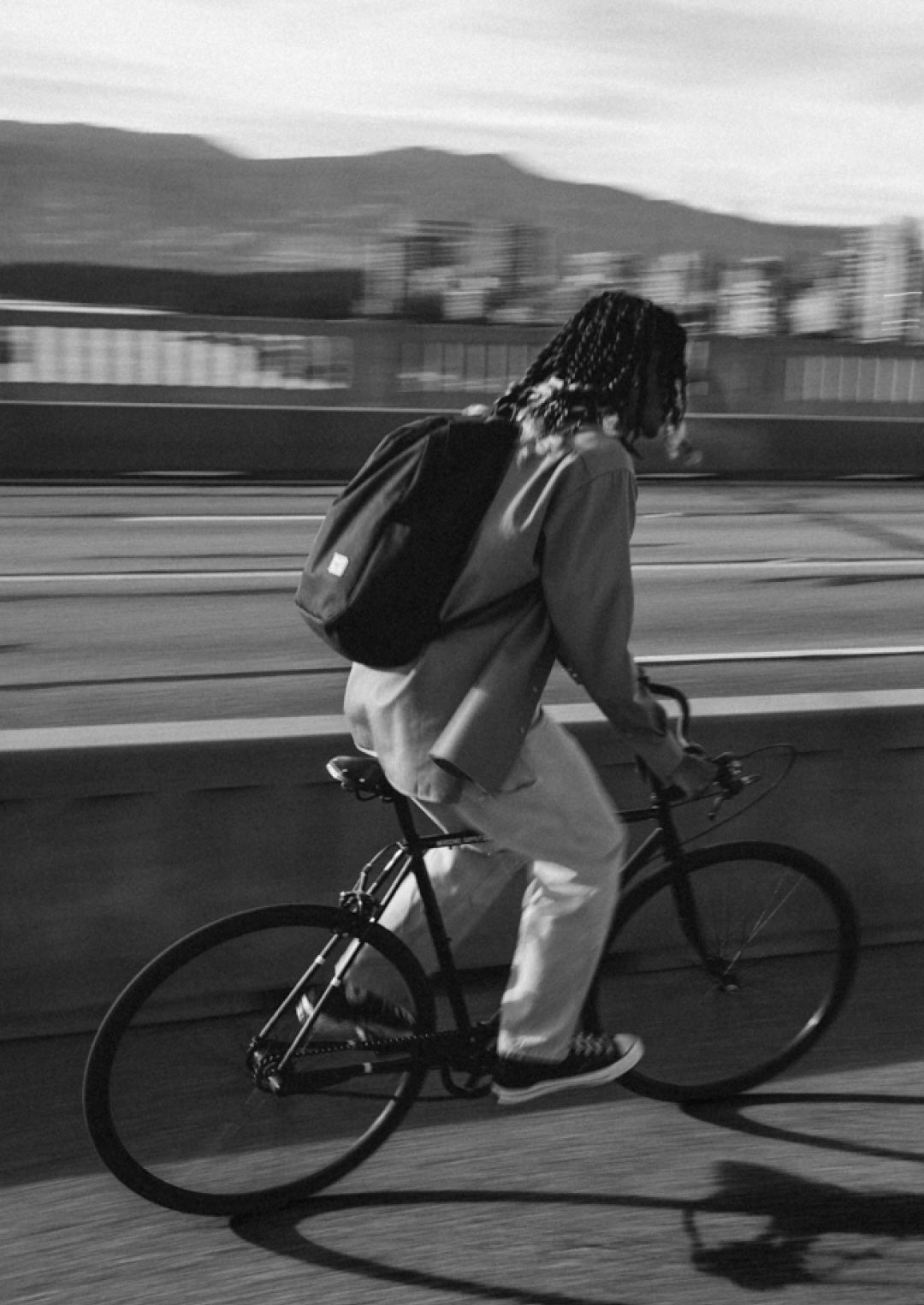 Person with a backpack riding a bicycle on a platform with a train in the background