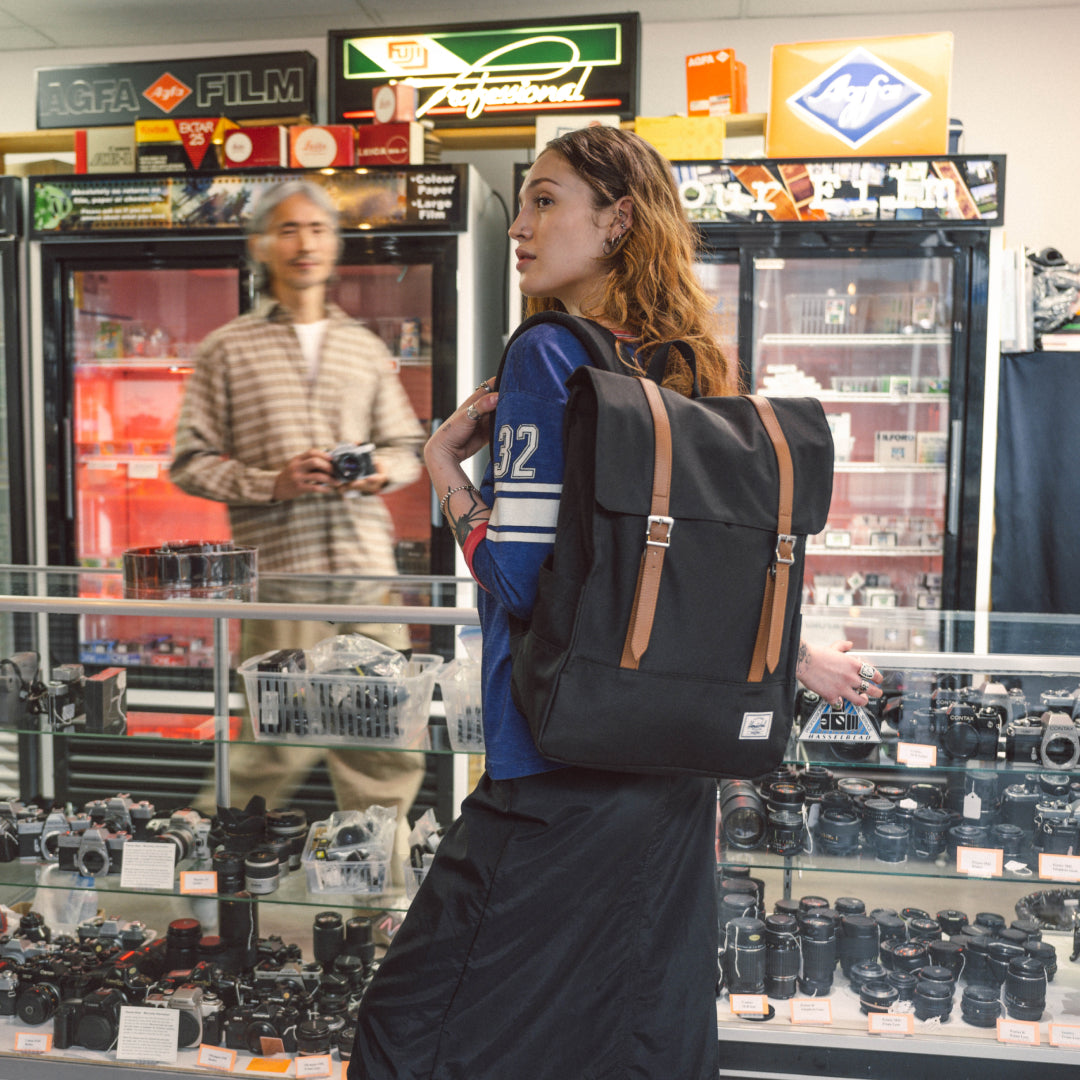 Woman with a black backpack in a store with camera equipment