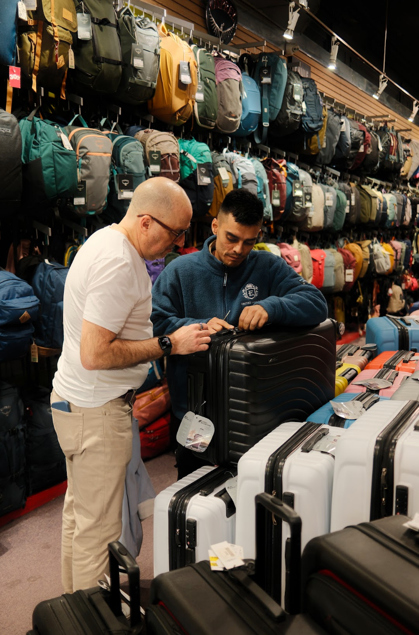 Two men examining suitcases in a luggage store.