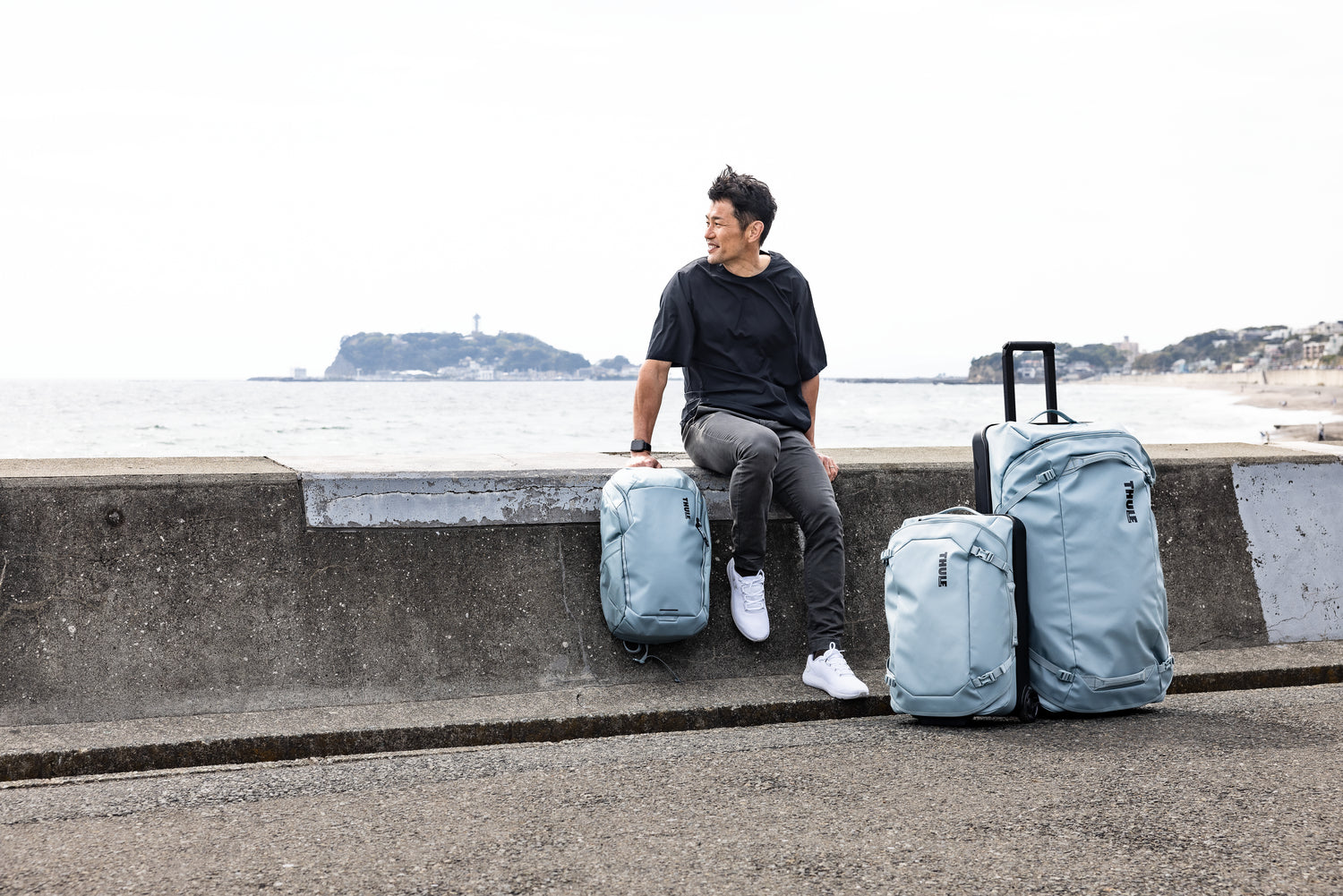 Man sitting with suitcases by a coastal area
